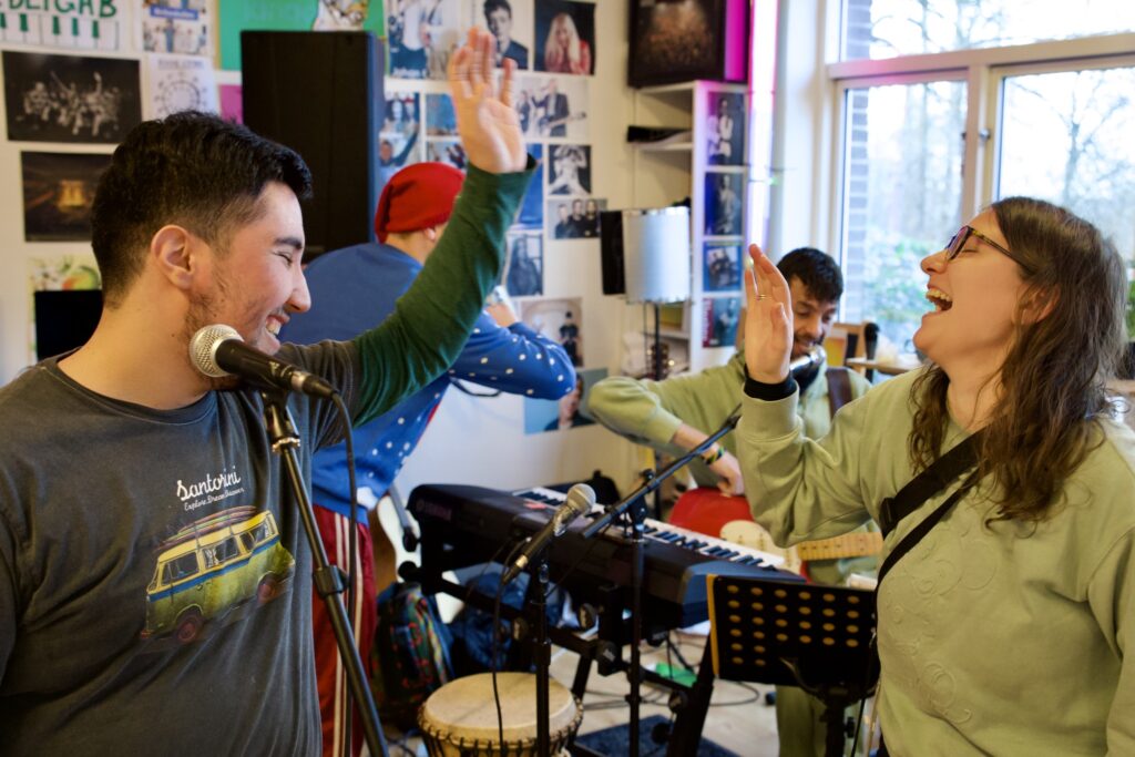 To personer deler en high-five i et rum udsmykket med plakater på bostedet Birkebakken