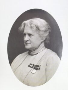 Vintage ovalt portræt af en ældre handicappet kvinde med hvidt hår iført en medalje på brystet.